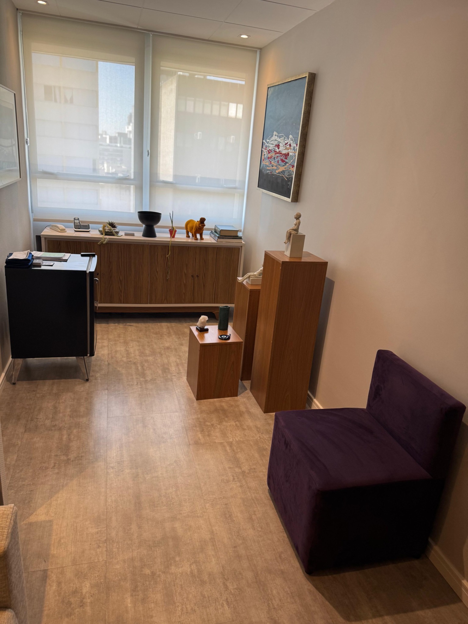 Sala de espera elegante, com sofás, poltronas confortáveis e obras de arte